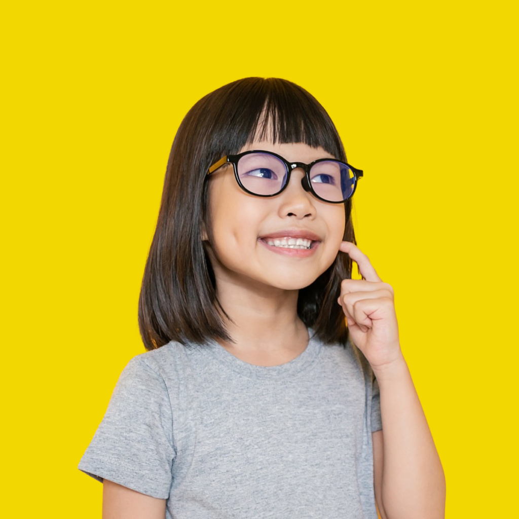 Child with glasses undergoing early orthodontic treatment pointing to her cheek