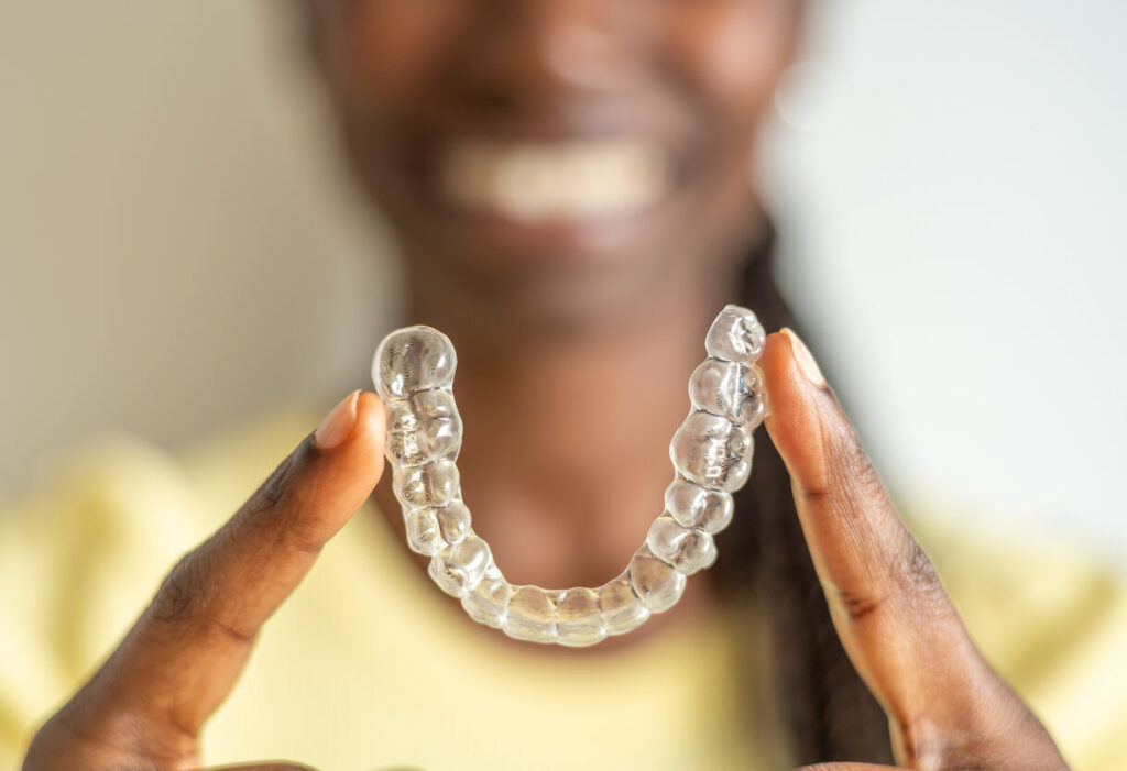 Young woman with Invisalign® in Chesapeake, VA holding her aligner between her index fingers