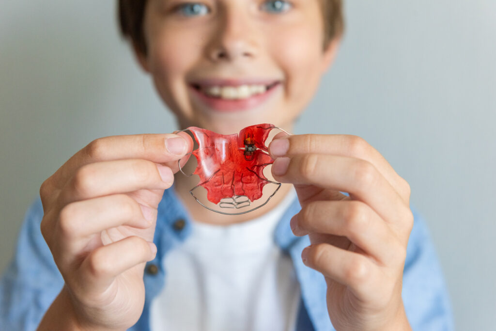 Child boy with Dental plate. Expansion of the jaw in a child. Color Orthodontic plate for children
